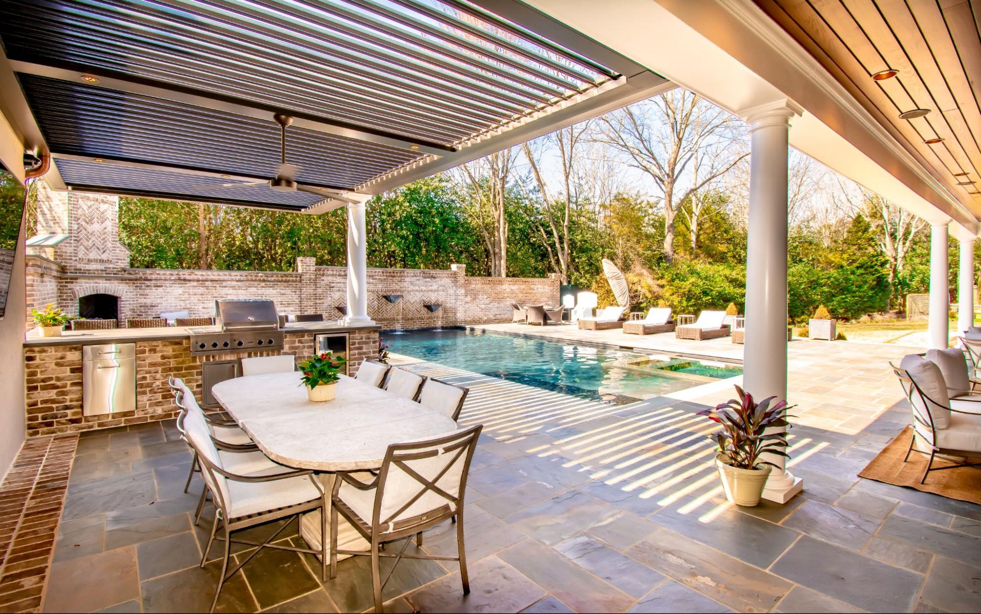 One of the modern pergola designs that features a StruXure pergola over a patio with an outdoor kitchen and dining area