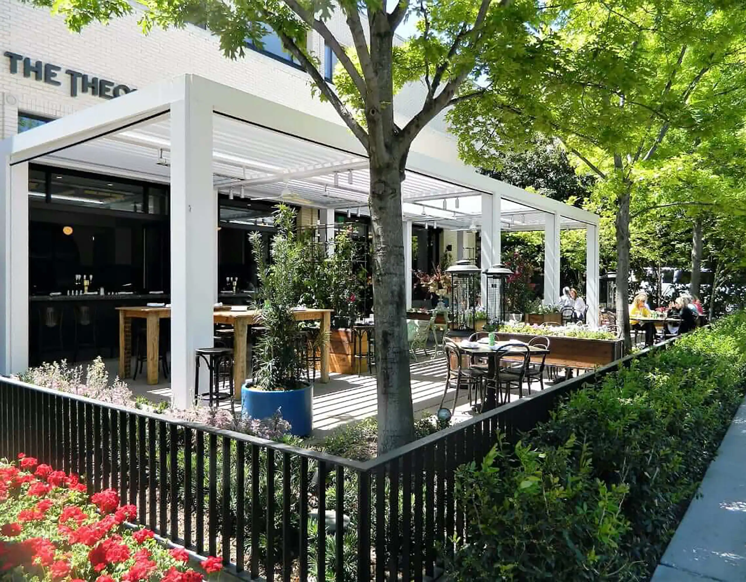 Photo of a StruXure Pivot 6 Pergola with a louvered roof that covers an outdoor dining and drinking area of a business