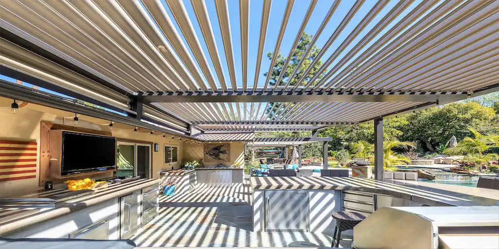 Photo of a StruXure pergola designed and built by StruXure NorCal that covers an outdoor entertainment area that includes an outdoor kitchen and dining area.