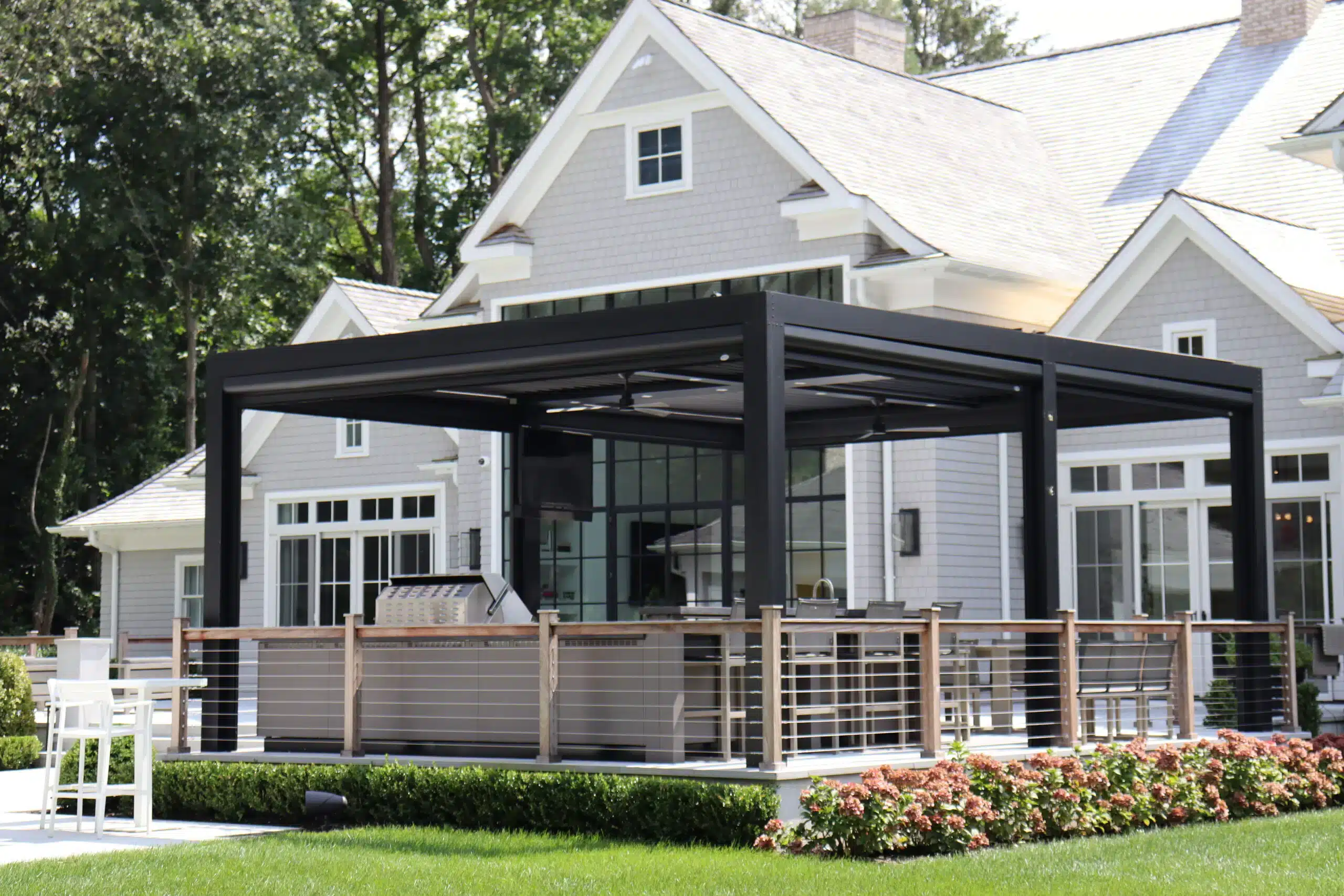 Photo of a StruXure motorized louvered pergola on a patio with an outdoor kitchen and dining area