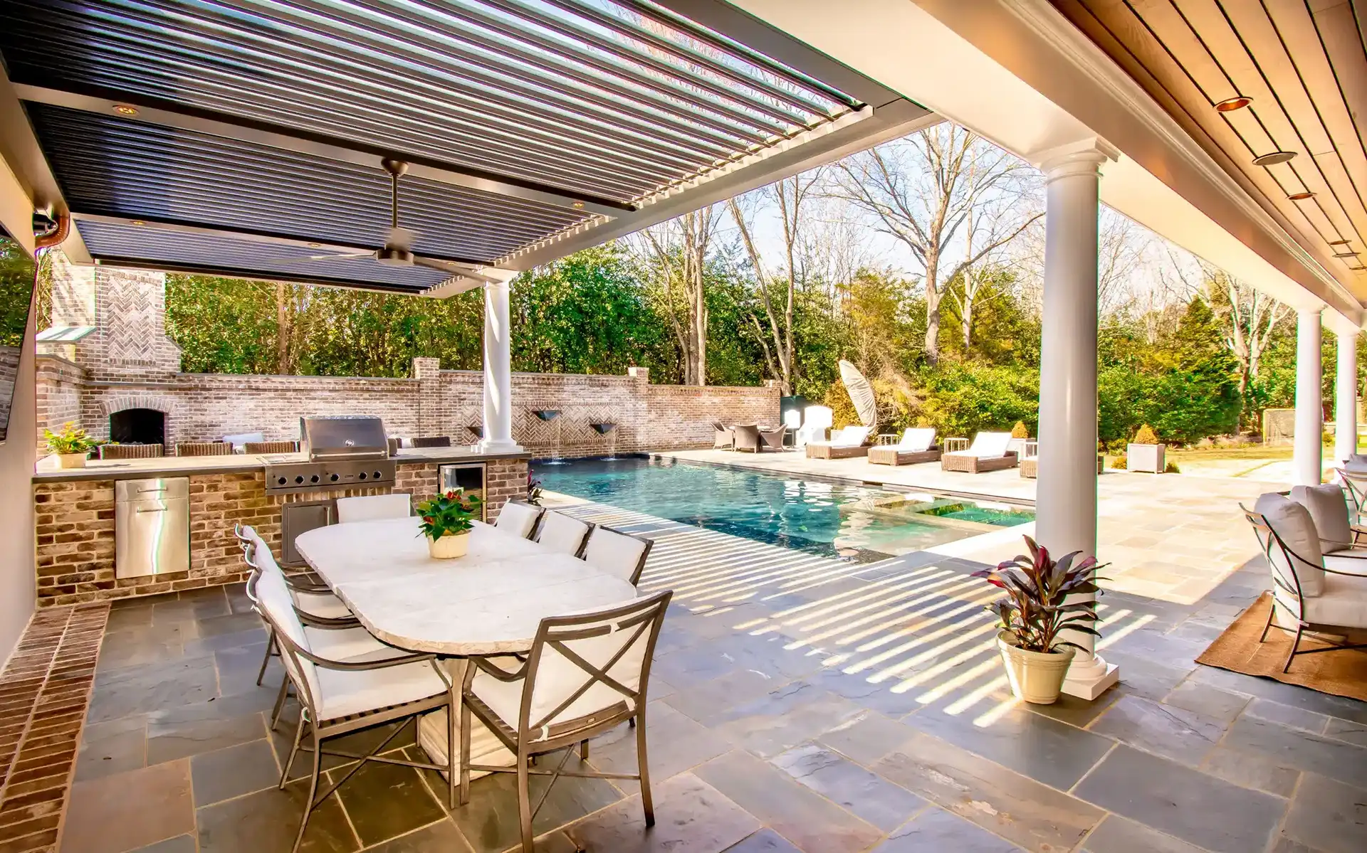 photo of a StruXure pool pergola covering an outdoor kitchen and outdoor dining area.