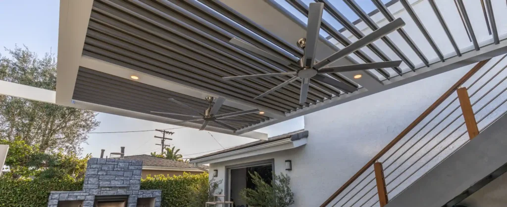 StruXure louvered roof pergola with ceiling fans, outdoor furniture, and an outdoor fireplaces - struxure-dealer in california