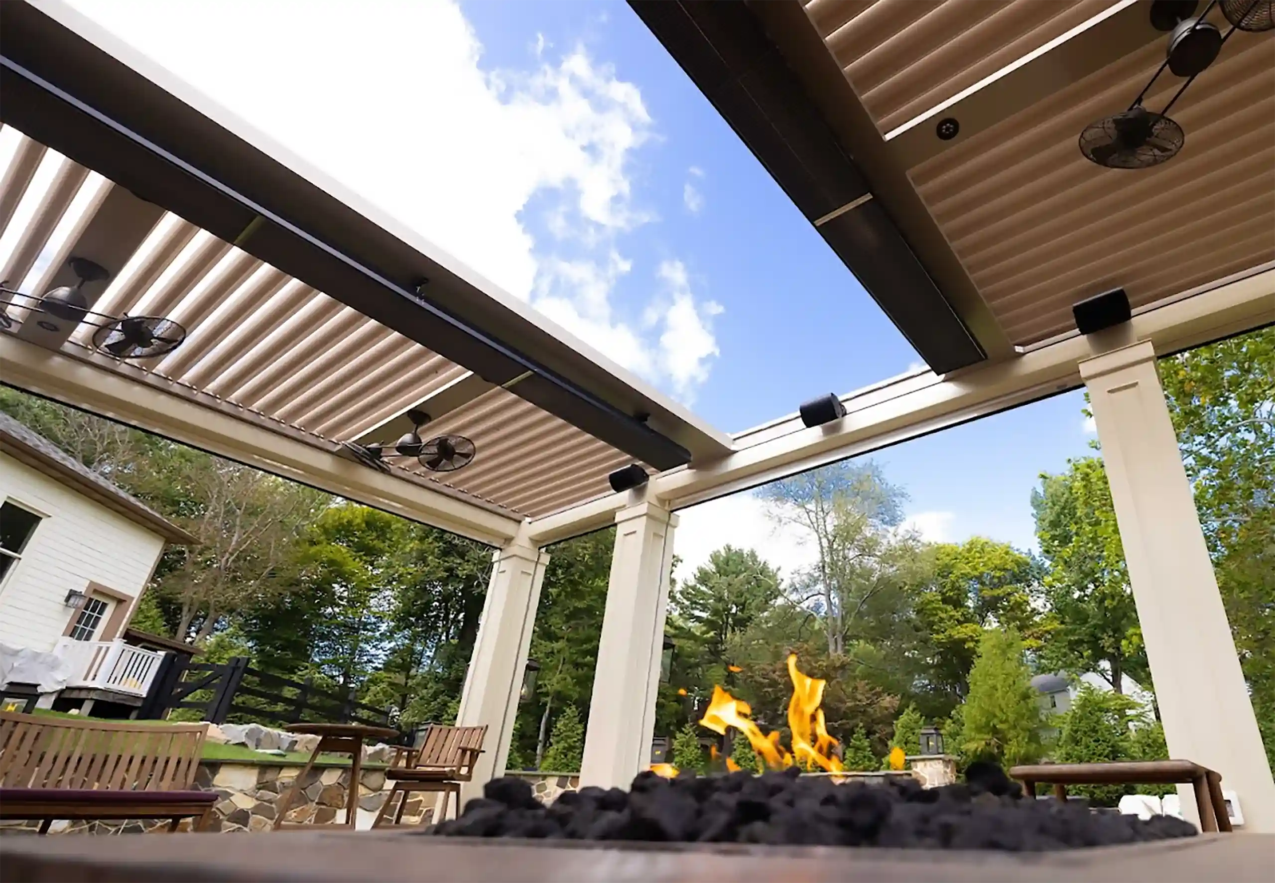 Photo of StruXure Pivot slide pergola with adjustable louvers, ceiling fans, and fire pit below. Should you get one of these? Check out our buying a pergola guide.