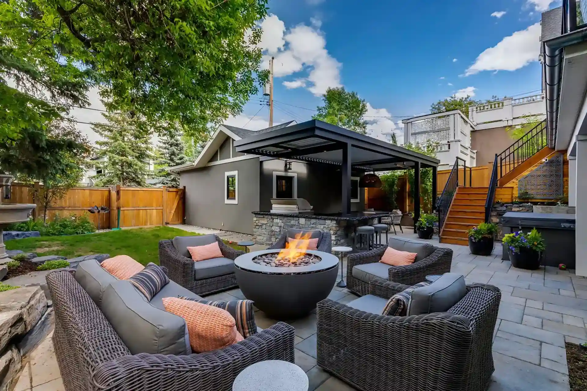 Photo of a pergola covering an outdoor kitchen with an outdoor living room and fire bowl.