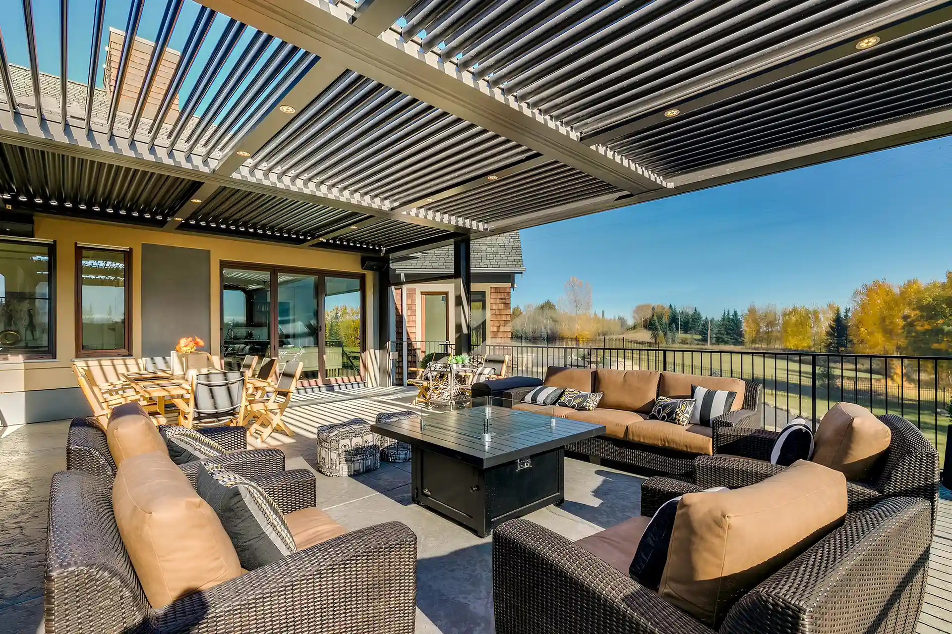 Photo of a StruXure louvered roof pergola with lighting, fire table, an outdoor dining area and an outdoor living room.